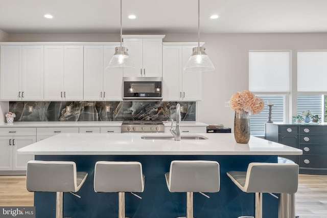 kitchen featuring sink, decorative light fixtures, white cabinetry, and a breakfast bar area