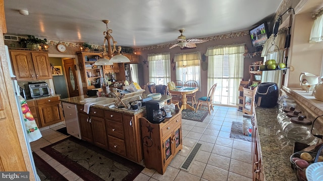 kitchen with dishwasher, dark stone countertops, a center island, and ceiling fan