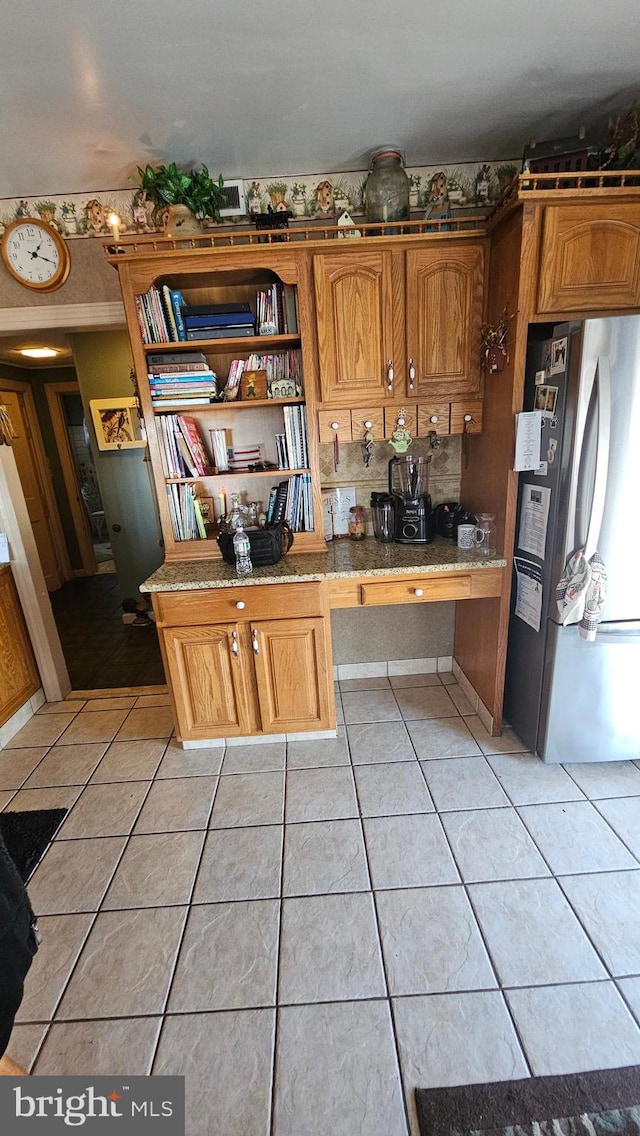 kitchen with light tile patterned floors and stainless steel refrigerator