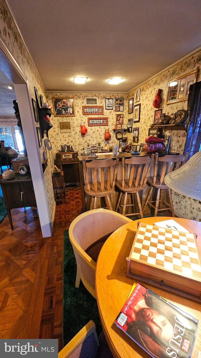 dining space with crown molding, a textured ceiling, dark parquet flooring, and bar area