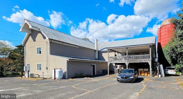 exterior space with cooling unit, a carport, and a balcony