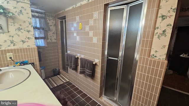 bathroom featuring a shower with door, tile walls, and vanity