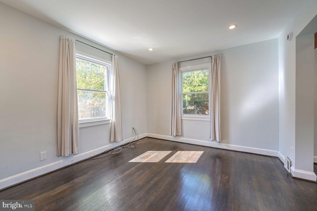 empty room with plenty of natural light and dark wood-type flooring