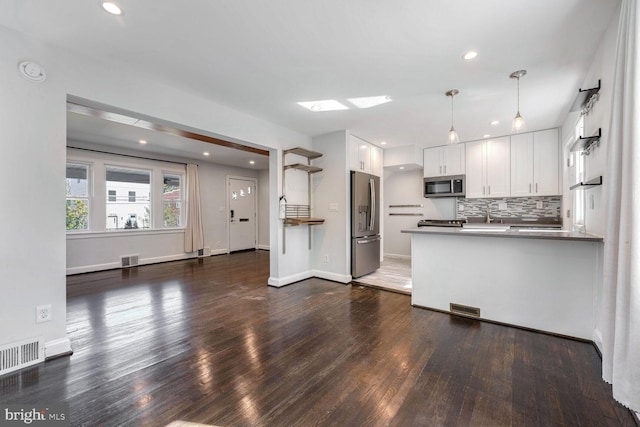 kitchen featuring white cabinets, stainless steel appliances, pendant lighting, and kitchen peninsula