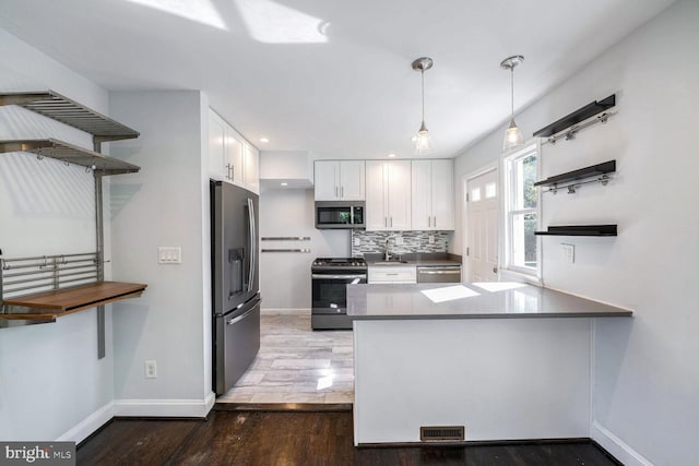 kitchen with stainless steel appliances, kitchen peninsula, dark wood-type flooring, and white cabinetry