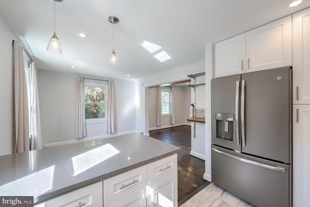 kitchen with wood-type flooring, white cabinets, stainless steel fridge, and dark stone counters