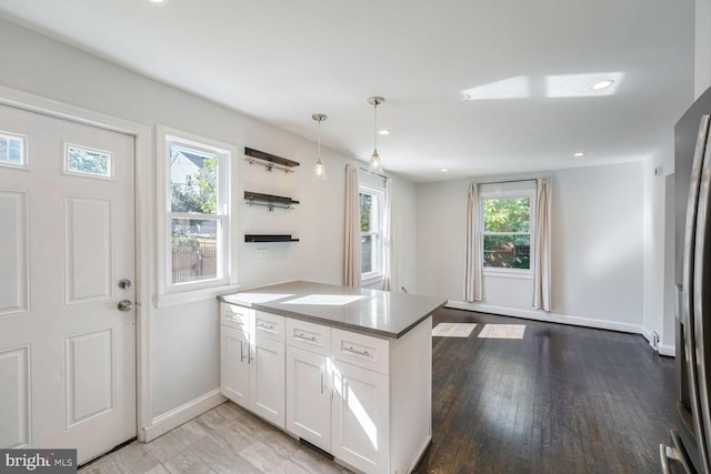 kitchen featuring wood-type flooring, white cabinets, pendant lighting, and kitchen peninsula