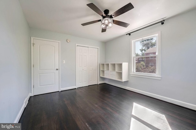 unfurnished bedroom featuring ceiling fan, dark wood-type flooring, and a closet