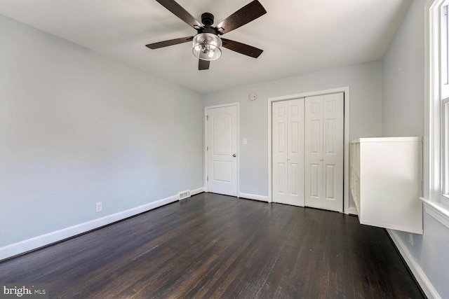 unfurnished bedroom with a closet, dark hardwood / wood-style flooring, and ceiling fan