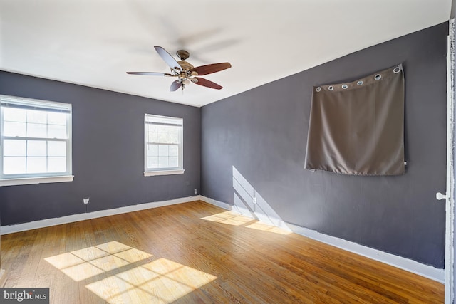 empty room featuring hardwood / wood-style flooring, a ceiling fan, and baseboards