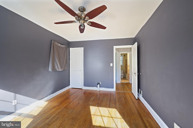 unfurnished room featuring wood-type flooring, a ceiling fan, and baseboards