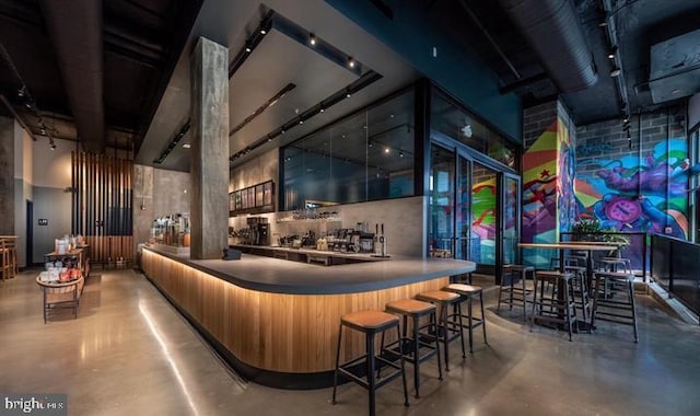 bar with concrete flooring and a high ceiling