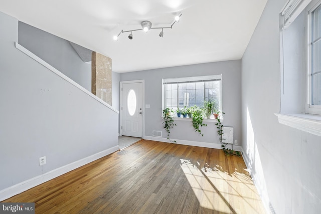 foyer entrance with wood-type flooring, baseboards, and stairway