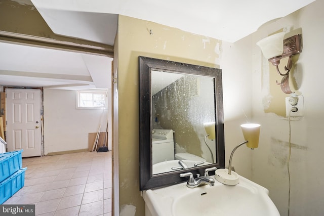 bathroom featuring tile patterned flooring, washer / clothes dryer, and sink