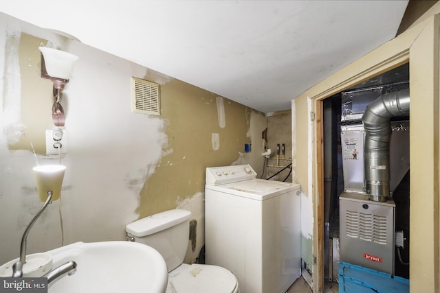 half bath with washer / clothes dryer, toilet, a sink, and heating unit