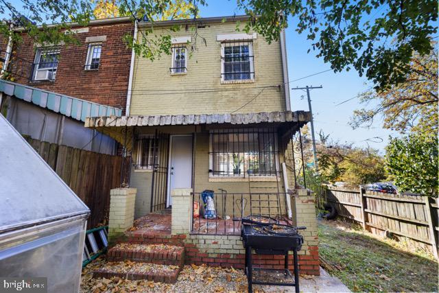 rear view of house with fence, brick siding, and covered porch
