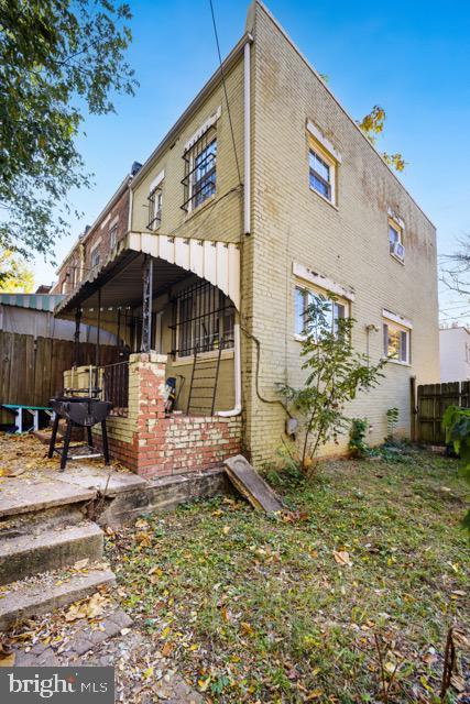 rear view of house featuring fence and brick siding