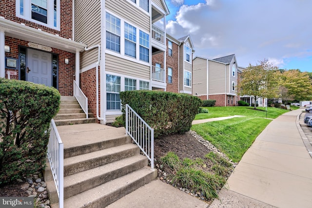 view of exterior entry featuring a yard, brick siding, and a residential view
