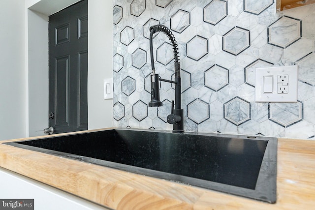 room details featuring sink, butcher block counters, and backsplash