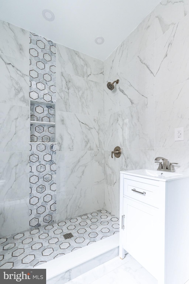 bathroom with tiled shower, tile walls, and sink