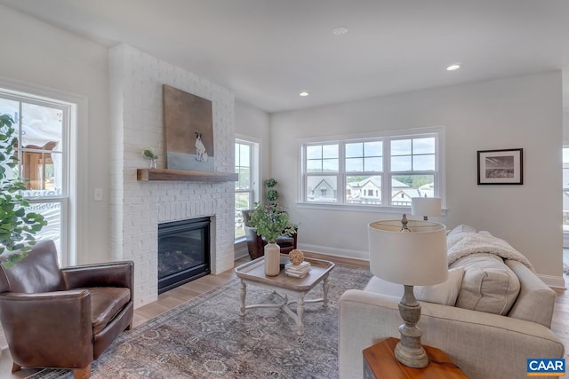 living room featuring plenty of natural light, a brick fireplace, and light wood-type flooring