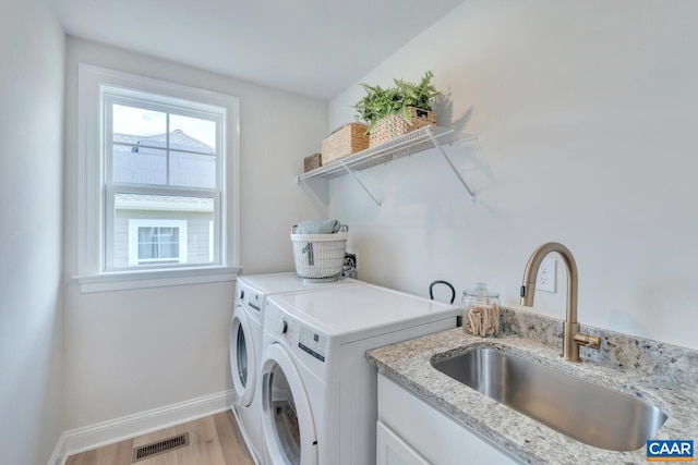 laundry area with washer and clothes dryer, light hardwood / wood-style flooring, and sink