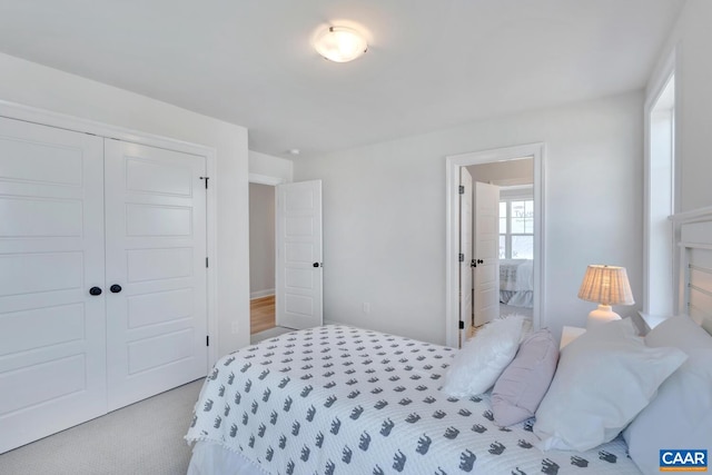 bedroom with light colored carpet, a closet, and ensuite bathroom