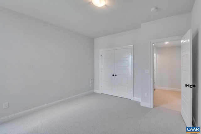 unfurnished bedroom with a closet and light carpet