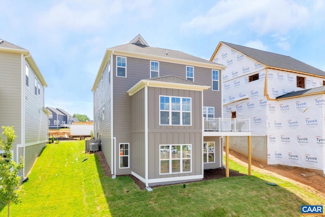 rear view of house with central AC and a lawn