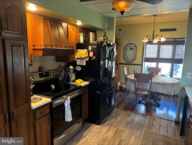 kitchen featuring black fridge, stainless steel electric range oven, an inviting chandelier, light hardwood / wood-style floors, and tasteful backsplash