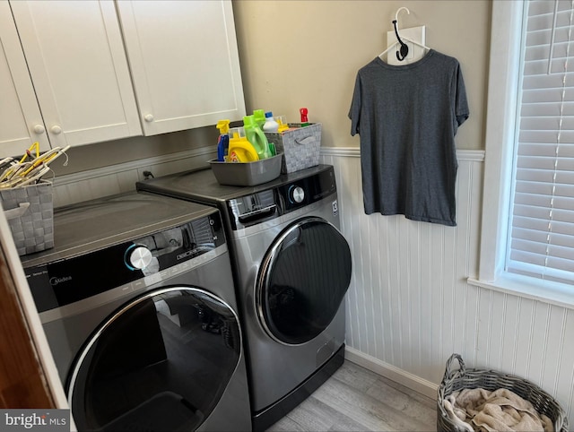 washroom featuring cabinets, washer and clothes dryer, and light wood-type flooring