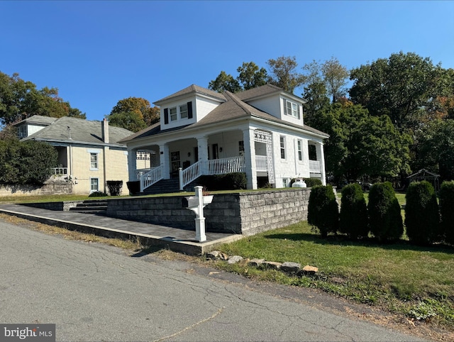 view of front of home with covered porch and a front lawn