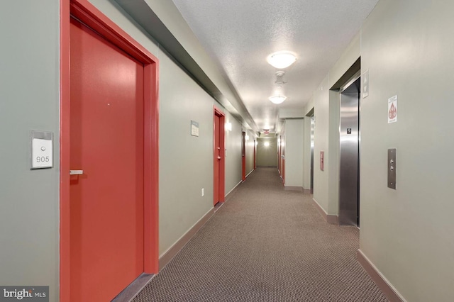 hallway with a textured ceiling, carpet, and elevator