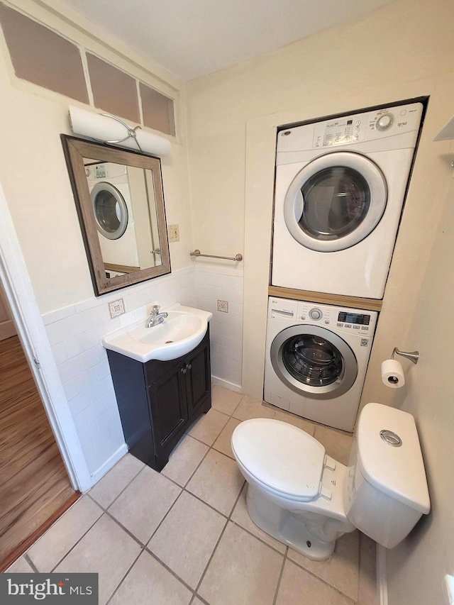 bathroom featuring vanity, stacked washer / dryer, tile walls, and tile patterned flooring