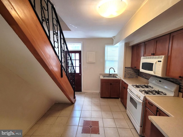 kitchen with white appliances, light tile patterned floors, tasteful backsplash, and sink