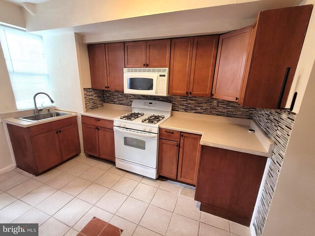 kitchen featuring decorative backsplash, sink, light tile patterned floors, and white appliances