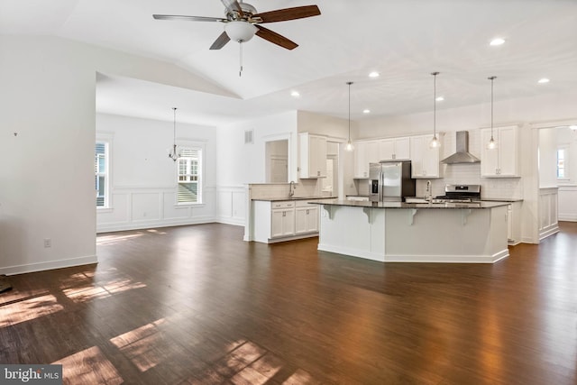 kitchen featuring dark hardwood / wood-style floors, wall chimney range hood, white cabinetry, and stainless steel appliances