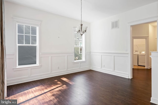 unfurnished dining area featuring washing machine and clothes dryer, a chandelier, and dark hardwood / wood-style flooring