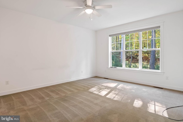 unfurnished room featuring ceiling fan, light colored carpet, and a wealth of natural light