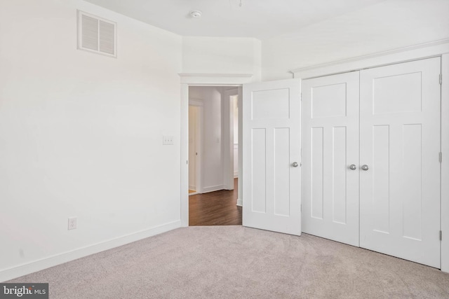 unfurnished bedroom with light carpet and a closet