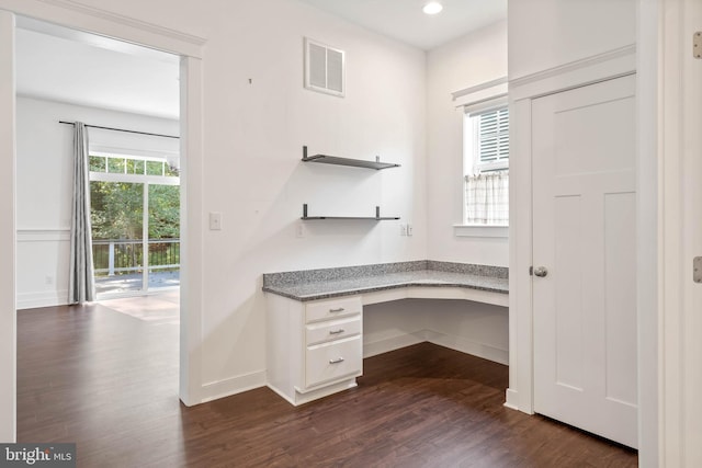 unfurnished office with dark hardwood / wood-style flooring and built in desk