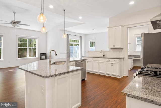 kitchen with pendant lighting, a center island with sink, sink, stainless steel appliances, and dark hardwood / wood-style floors