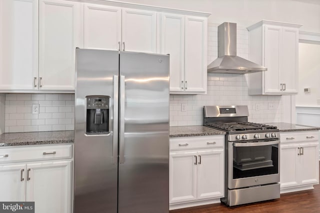 kitchen with appliances with stainless steel finishes, wall chimney range hood, and white cabinetry