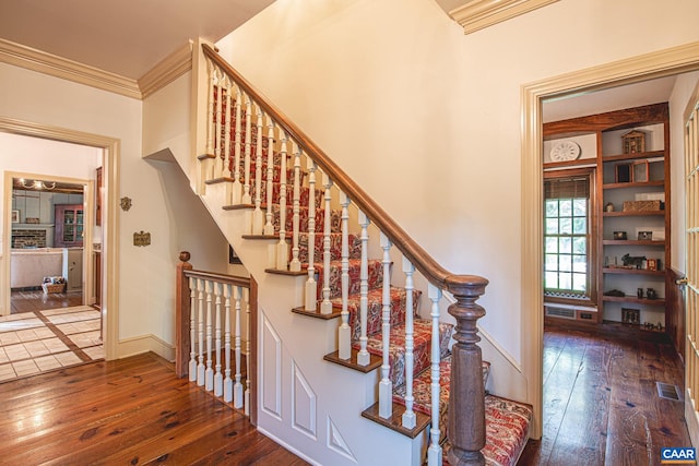 staircase featuring wood-type flooring and ornamental molding