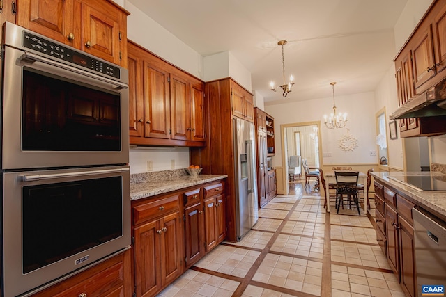 kitchen with light stone counters, stainless steel appliances, light tile patterned flooring, an inviting chandelier, and decorative light fixtures