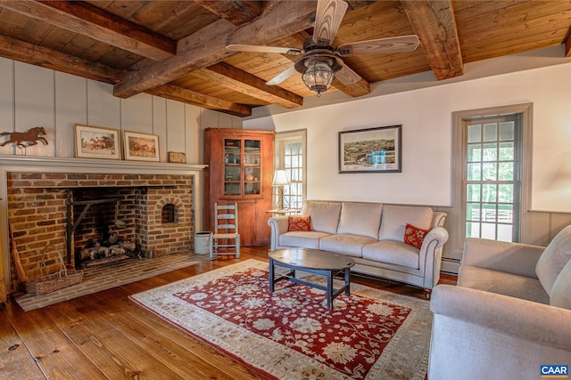 living room featuring a brick fireplace, ceiling fan, hardwood / wood-style flooring, wooden ceiling, and beam ceiling