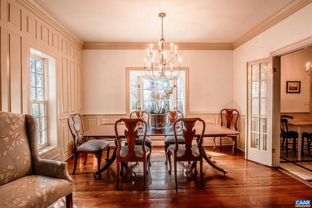 dining area with ornamental molding, a notable chandelier, and dark hardwood / wood-style flooring