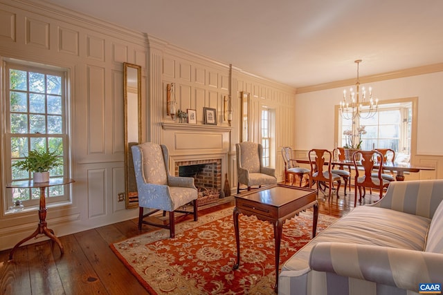 living room with a fireplace, ornamental molding, dark hardwood / wood-style floors, and a chandelier