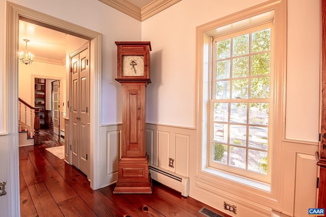 interior space with hardwood / wood-style flooring, crown molding, a baseboard heating unit, and an inviting chandelier