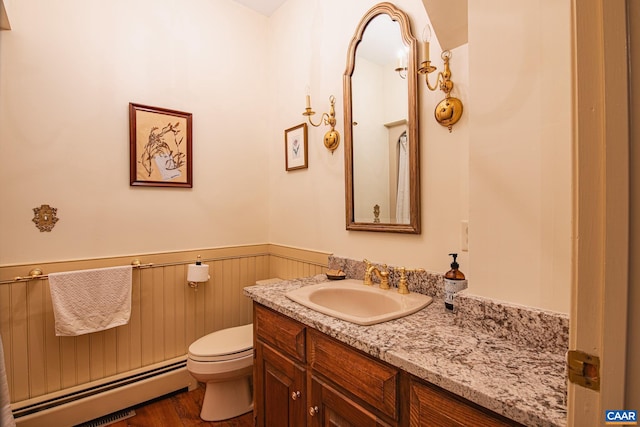 bathroom featuring baseboard heating, hardwood / wood-style flooring, vanity, and toilet